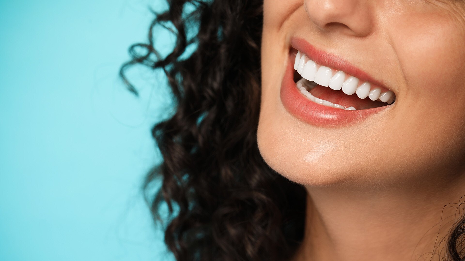 Close up shot of the teeth of a smiling woman on a blue background