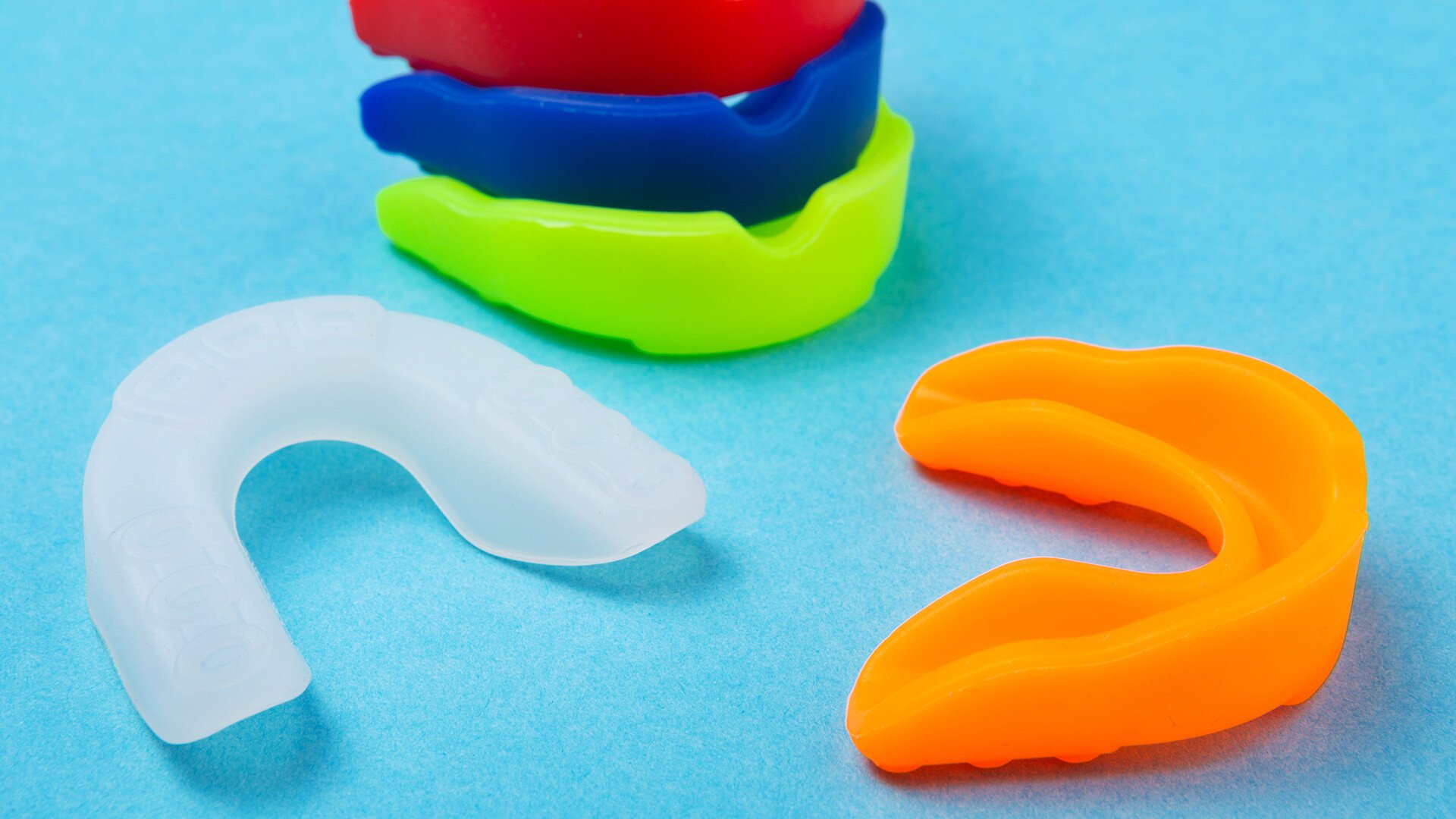 A close up image of a stack of mouthguards in an assortment of colors 