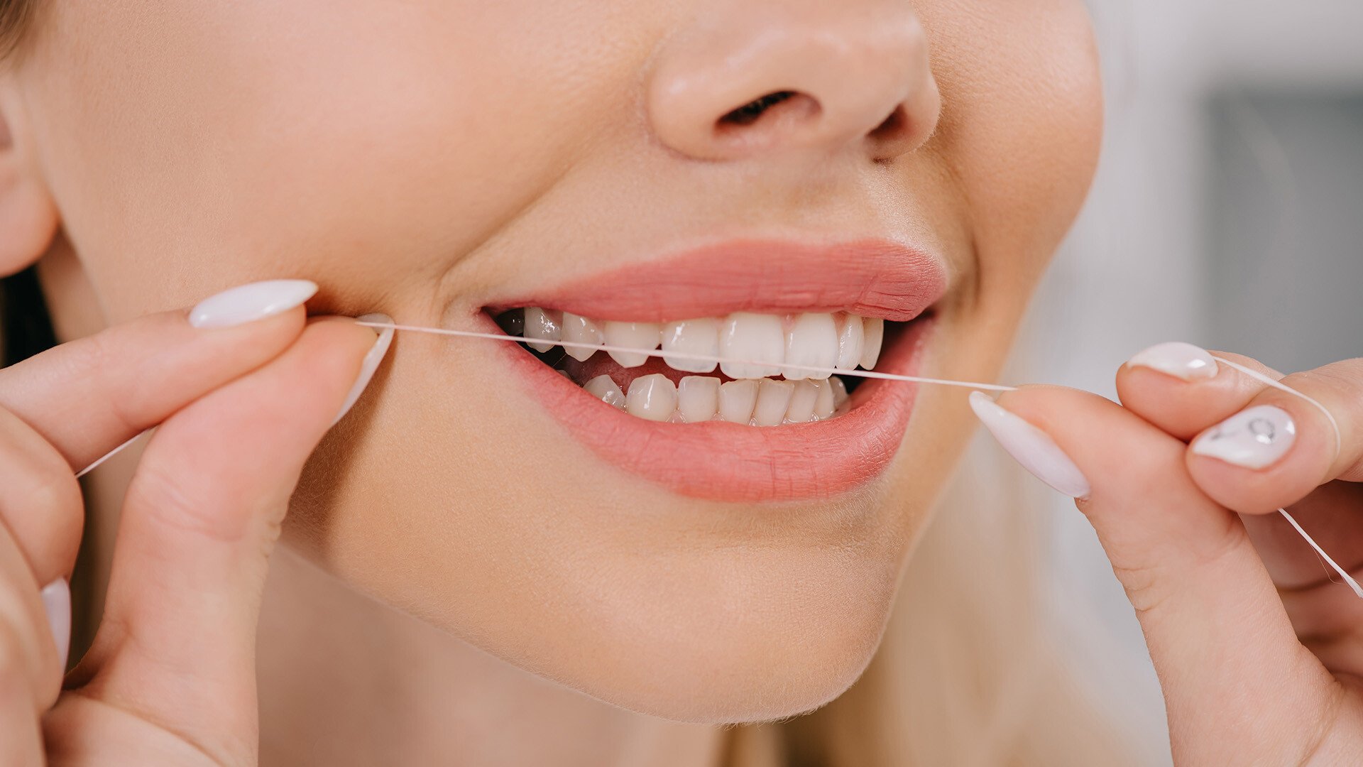 Close up image of a woman flossing her teeth 