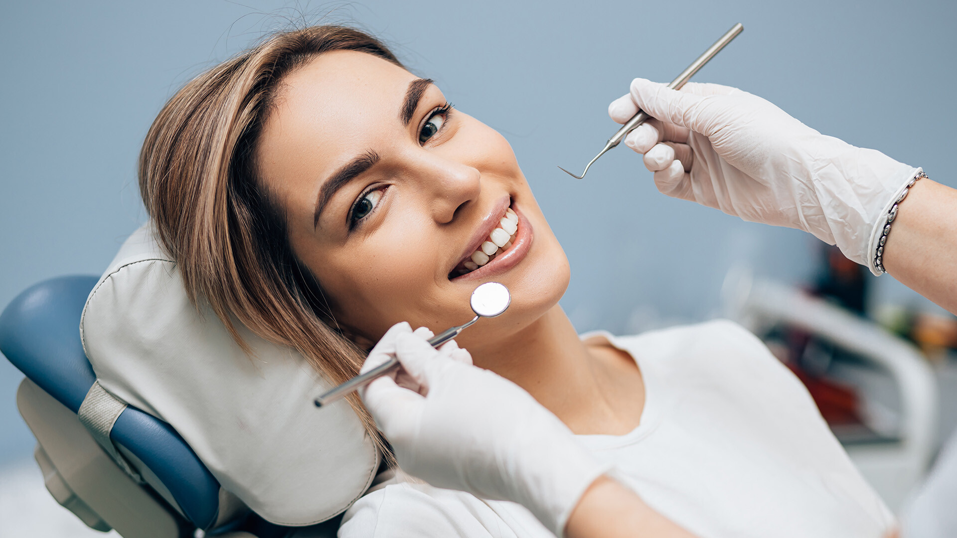 Portrait of a young woman smiling and sitting in a dental chair for an examination 